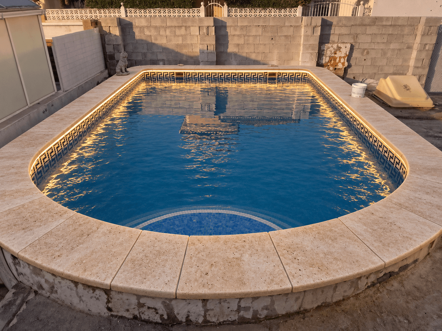 Bordillo de piscina revestido en travertino natural con iluminación LED integrada