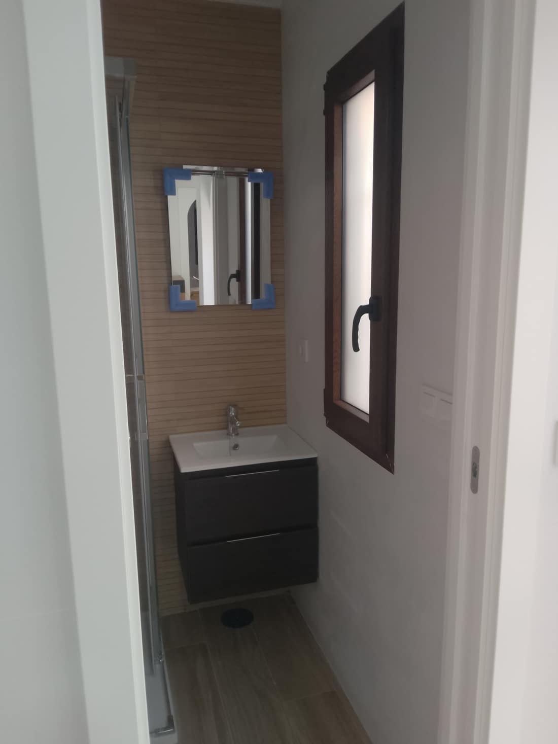 Mueble de baño en tono oscuro con lavabo, espejo y ventana nueva