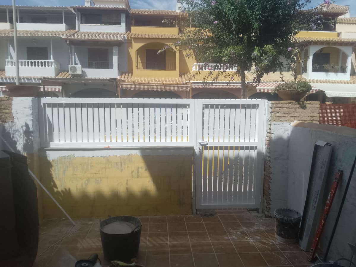 Nuevo cerramiento de aluminio blanco en la entrada de la vivienda, durante su instalación