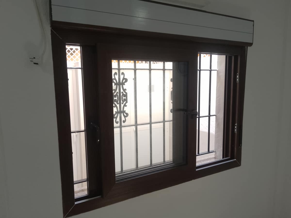 Ventana de PVC nueva con persiana, con la reja original conservada
