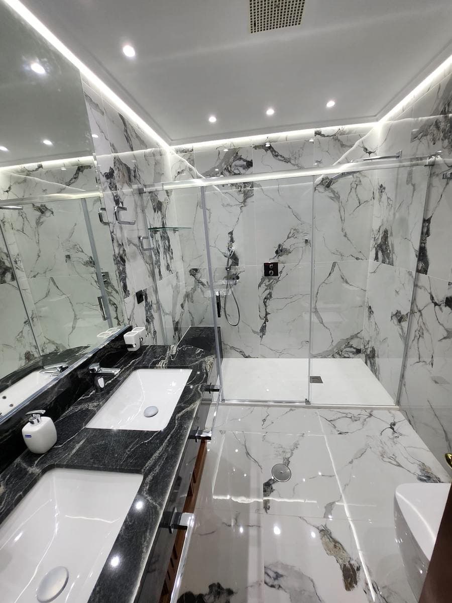 Baño terminado en Cartagena, con ducha, mampara de cristal y revestimiento de mármol