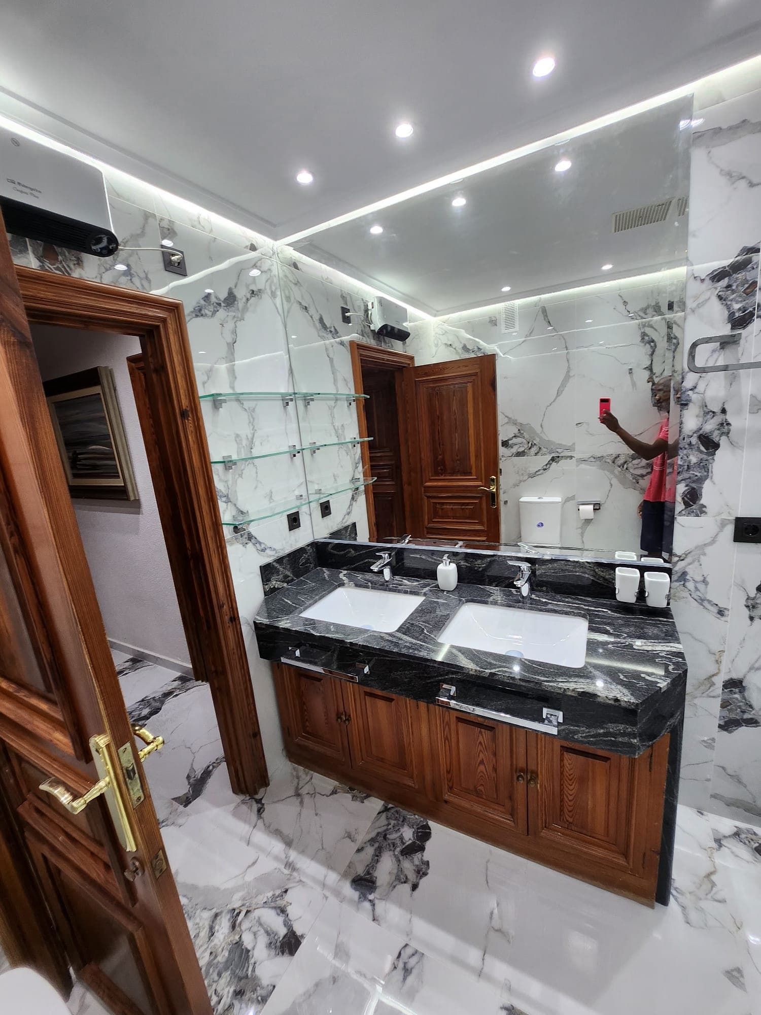 Baño terminado con mármol y doble lavabo, vista desde la puerta de acceso