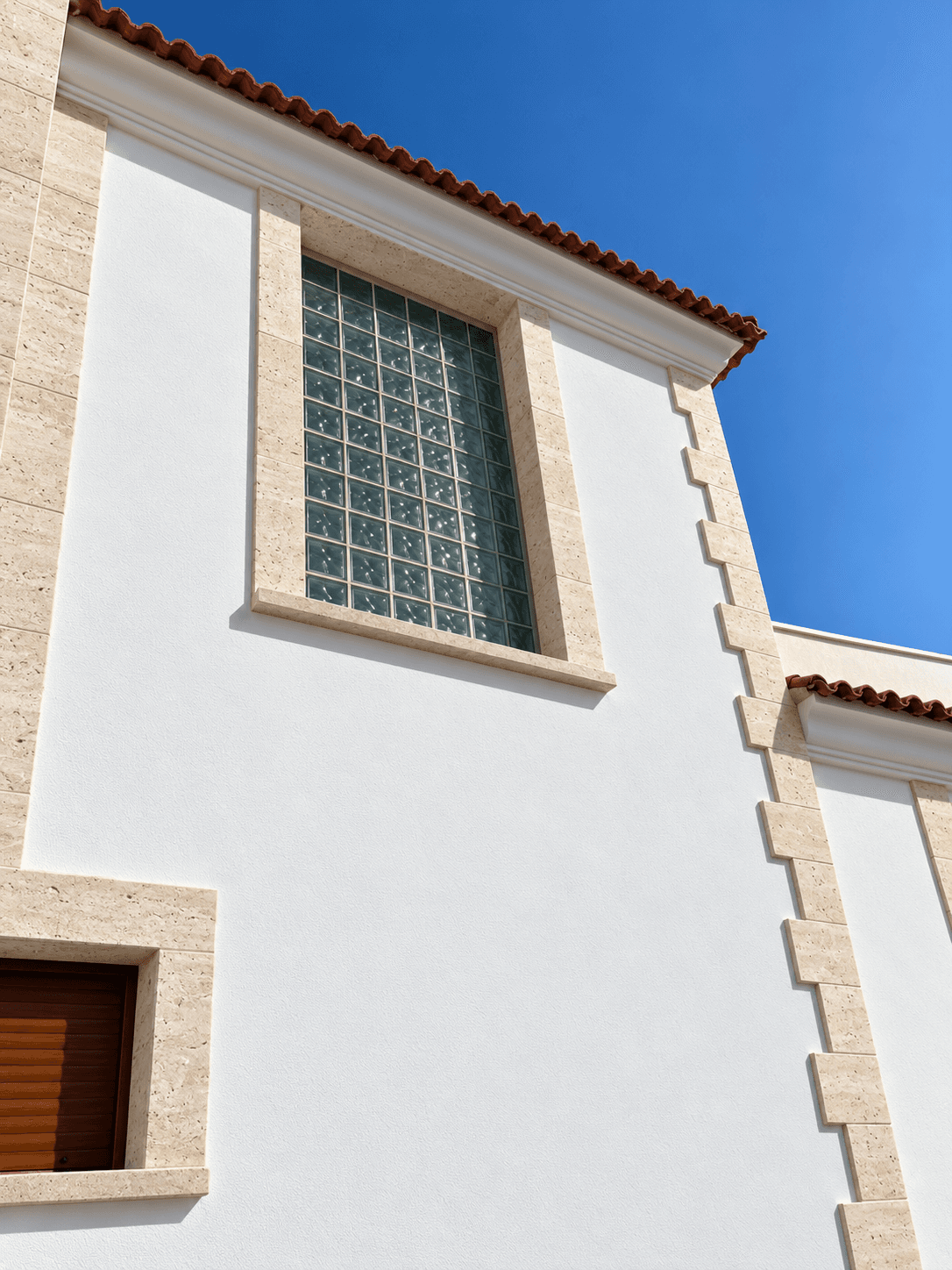 Fachada terminada con revestimiento blanco y recercados de ventana en travertino