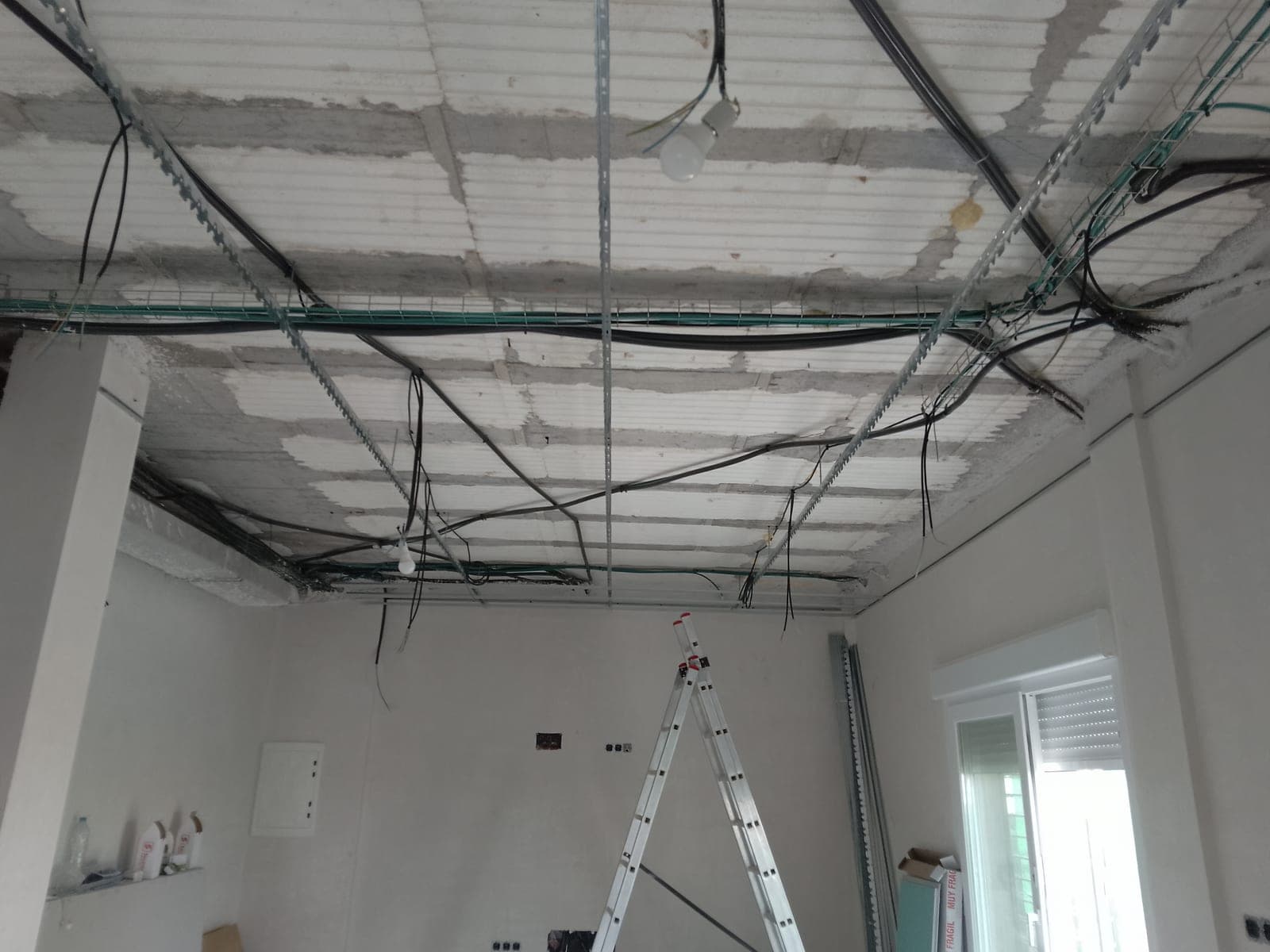 Techo original con el forjado al descubierto, cableado eléctrico colgando y un cuadro eléctrico provisional en la pared