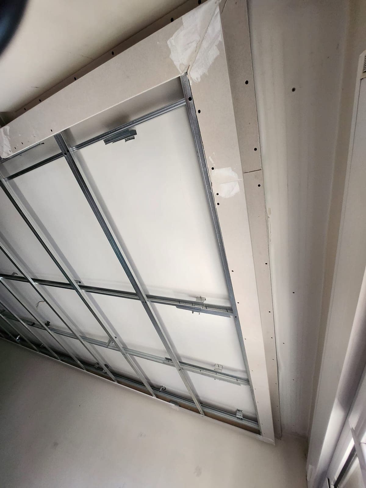Falseado perimetral de Pladur en construcción, con el escalón del techo formado junto a la estructura metálica, cerca de una ventana