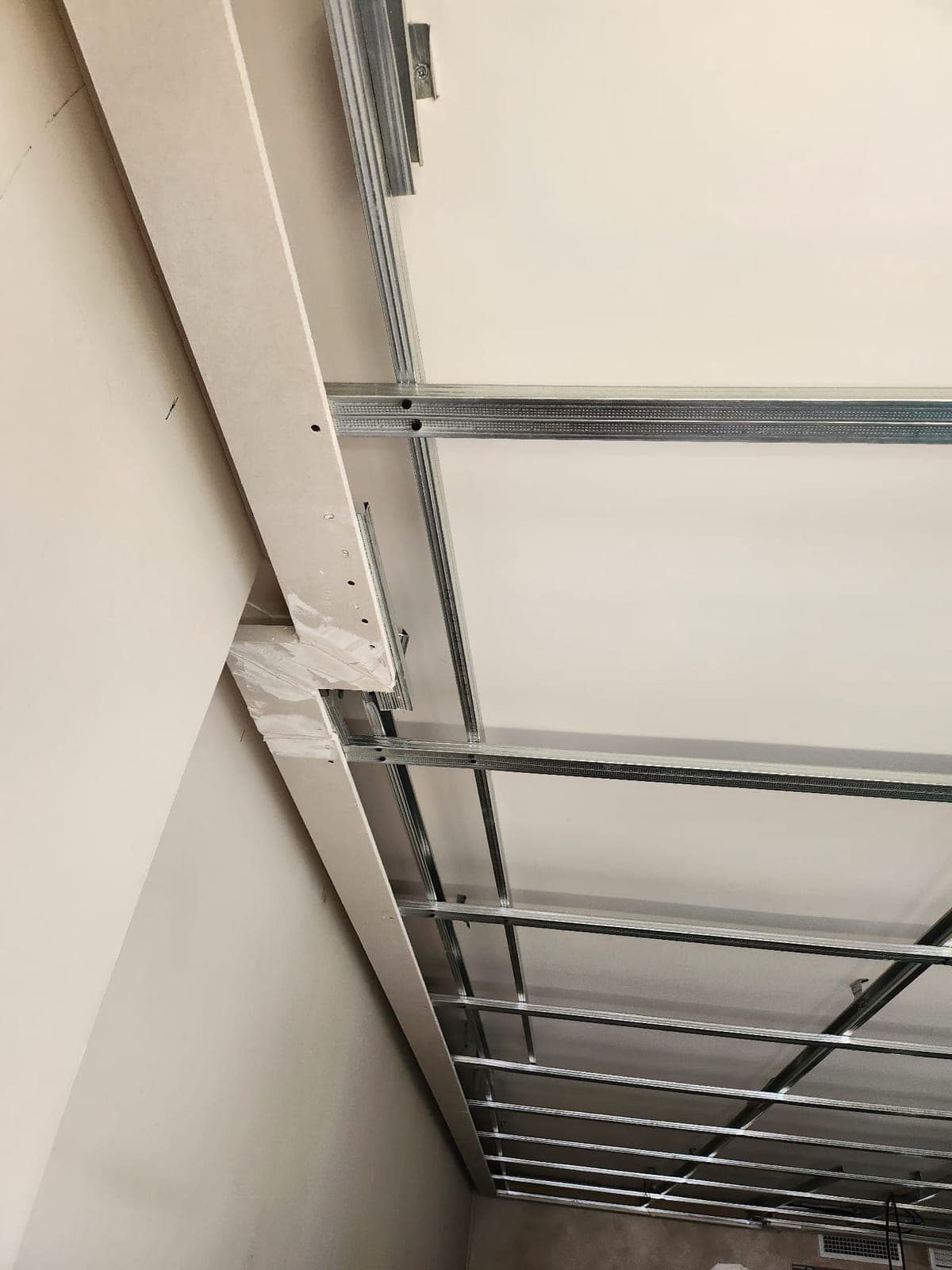 Detalle del rebaje del falseado perimetral en el falso techo, con la estructura metálica visible detrás, donde después se aloja la tira led
