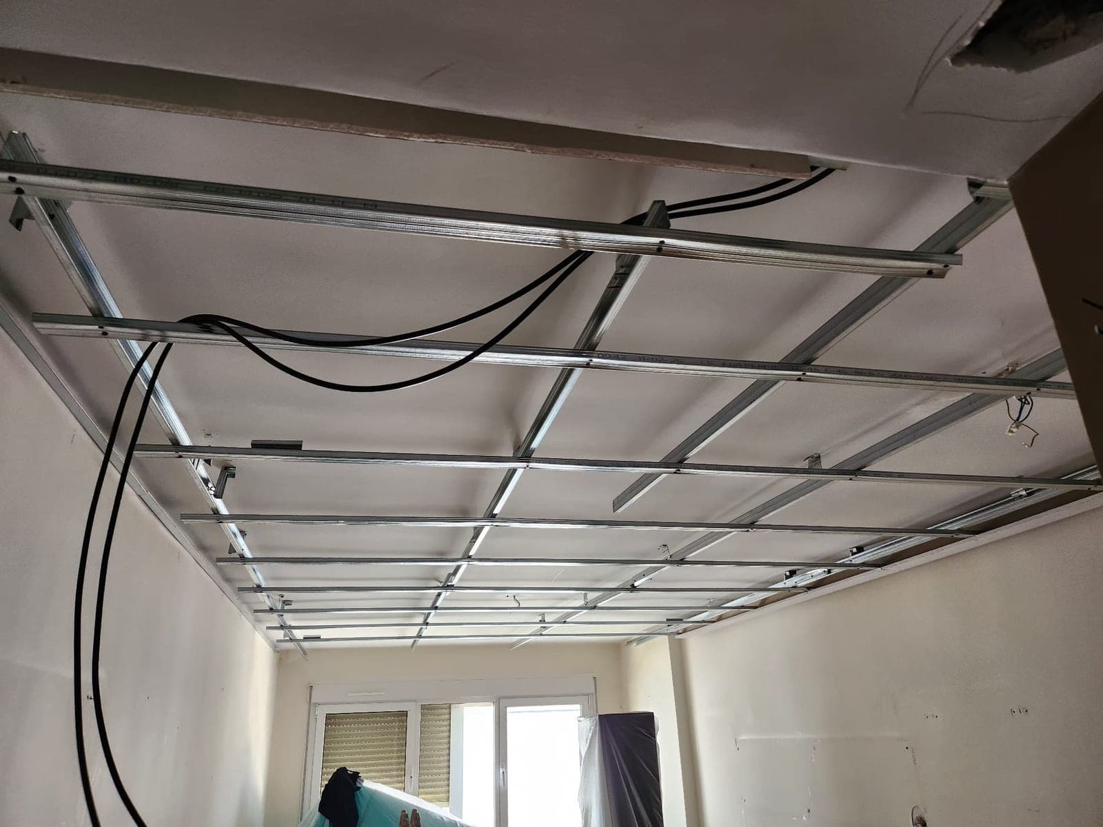 Estructura metálica del falso techo montada en otra estancia de la vivienda, con el cableado eléctrico ya organizado