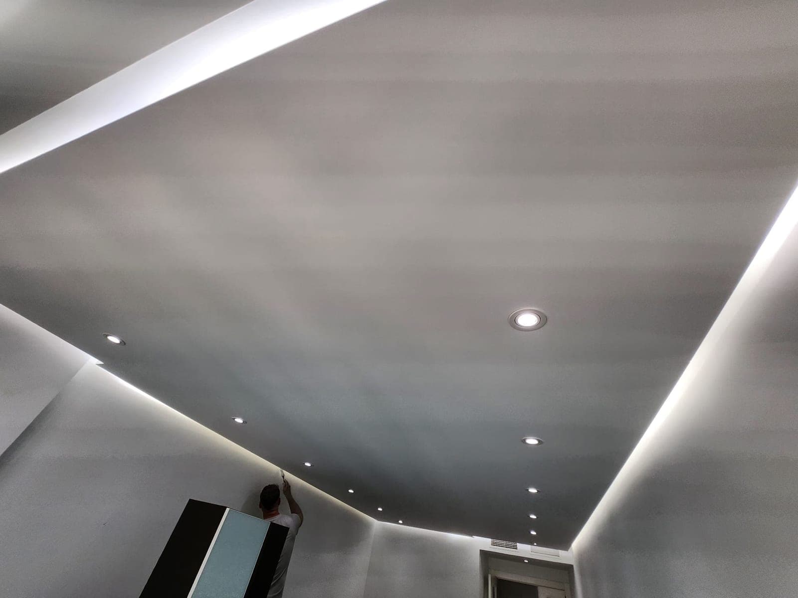 Esquina de una habitación con el falseado perimetral de iluminación indirecta y focos empotrados, con los trabajos de pintura en marcha