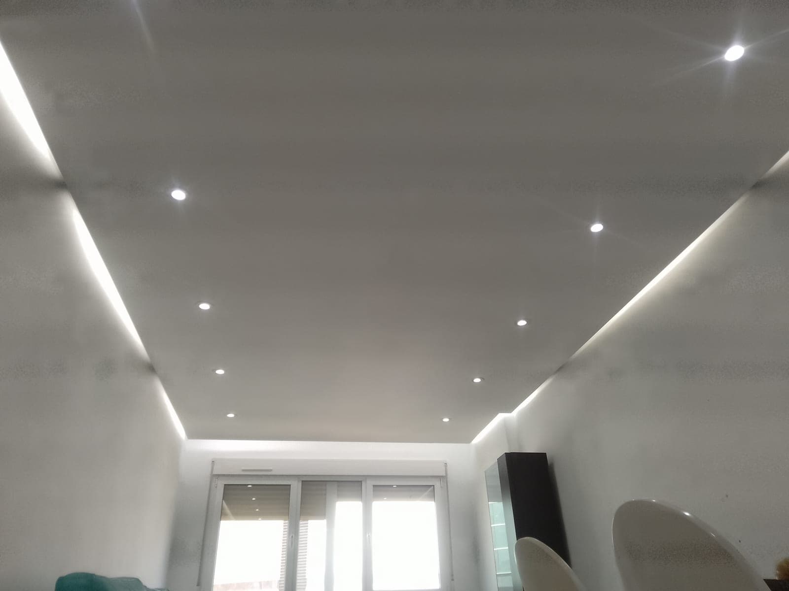 Salón con el falseado perimetral terminado: iluminación led indirecta recorriendo el techo junto a focos empotrados