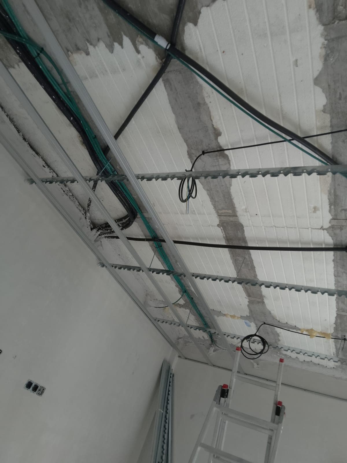 Perfiles metálicos del techo recién colocados, con el cableado eléctrico y el aislamiento entre forjados todavía a la vista