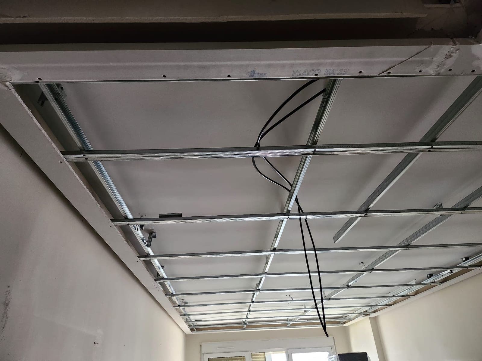 Placa de Pladur colocada sobre la estructura metálica del techo, con el nombre del fabricante impreso todavía visible