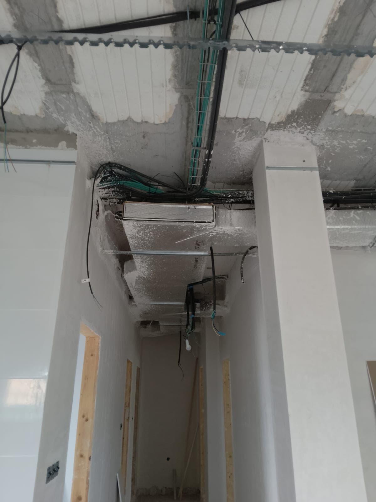 Pasillo con la rejilla de salida de aire acondicionado ya instalada en el techo, mientras el resto de la superficie sigue sin cerrar
