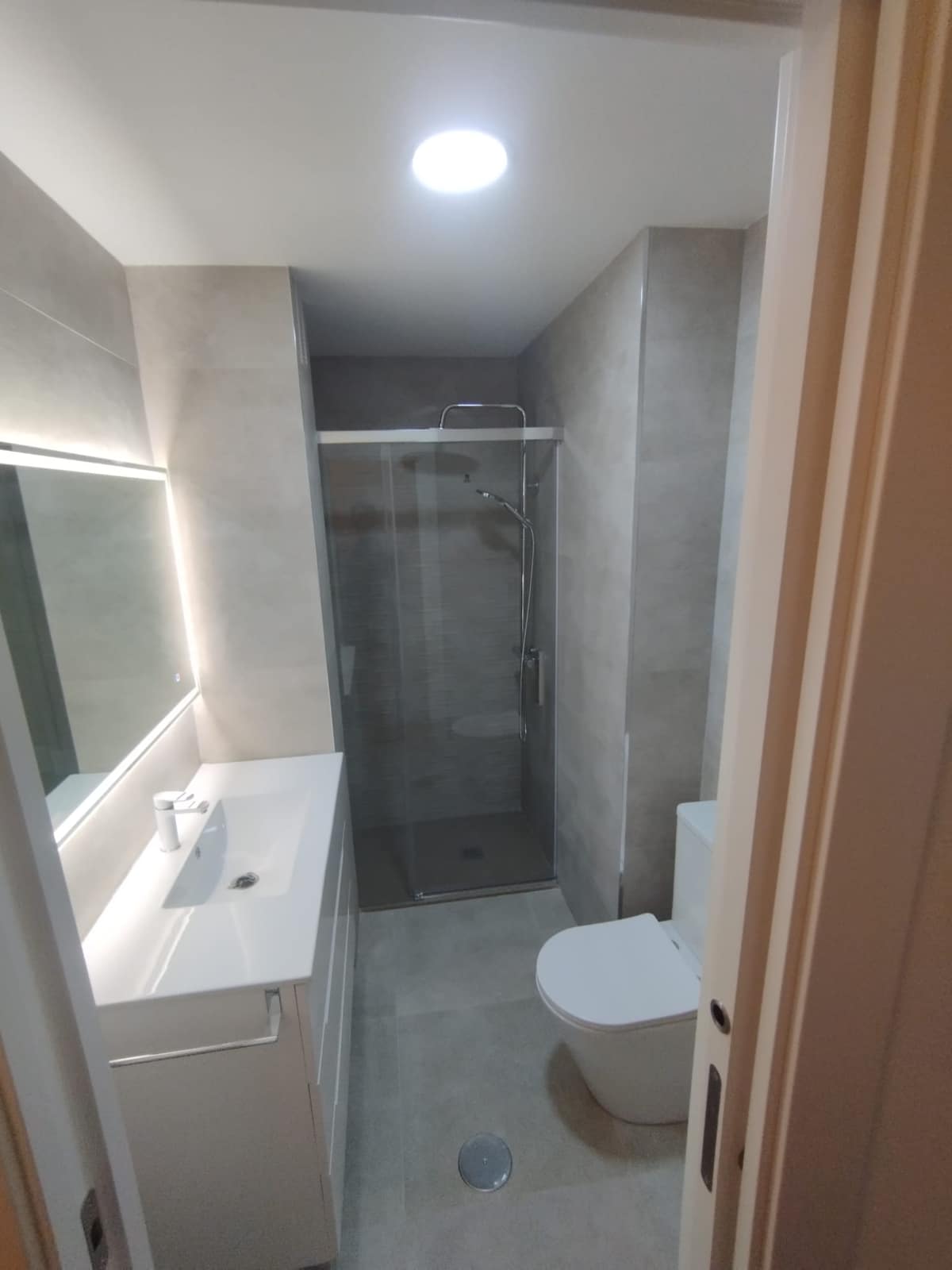 Baño terminado tras la reforma en Cartagena, con mueble de lavabo y espejo
